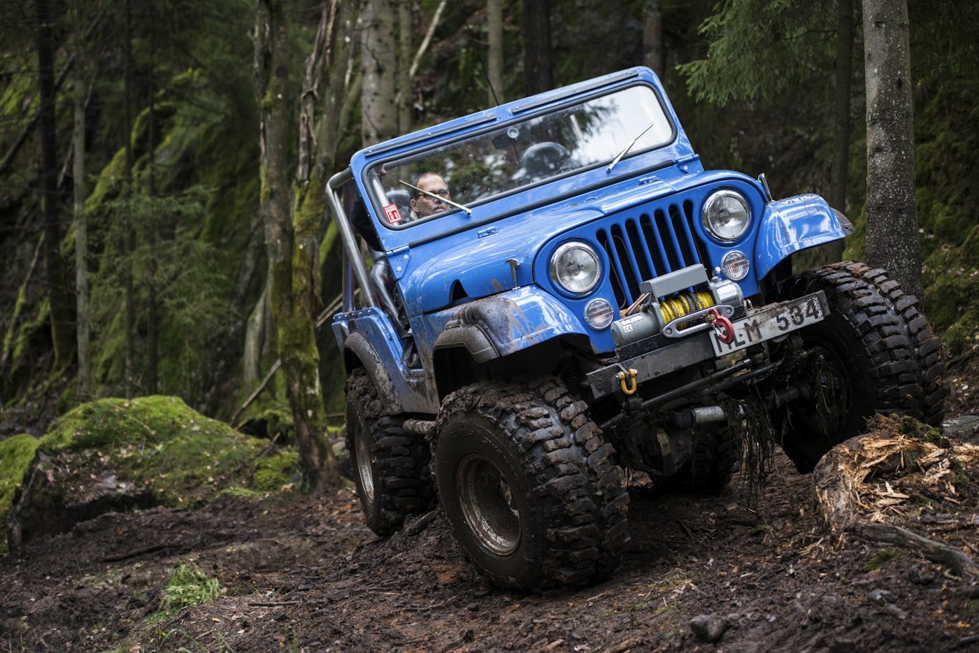 Jeep climbing a muddy forest trail